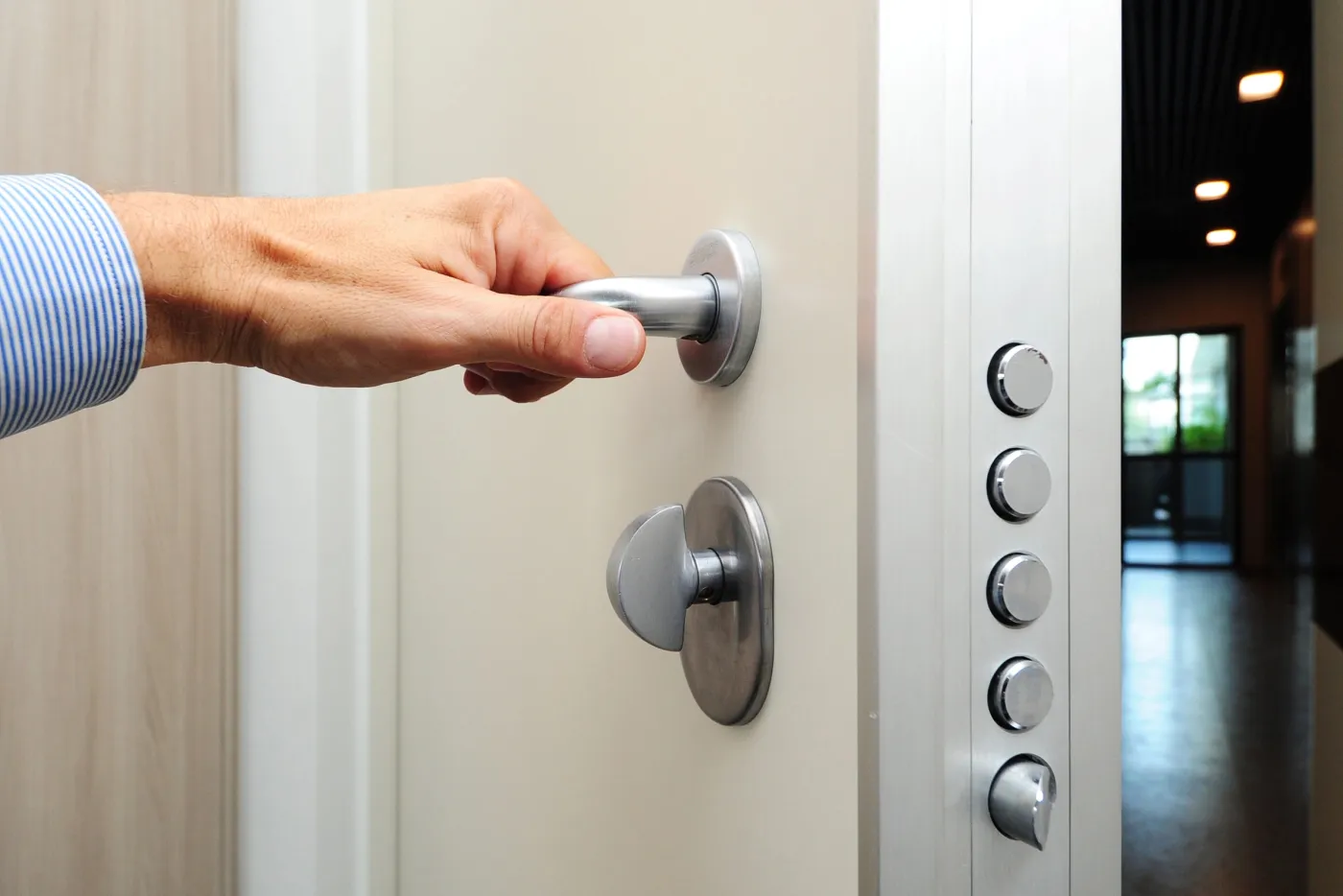 Main sur la poignée d'une porte blindée à serrure multipoint dans une copropriété d'Issy-les-Moulineaux